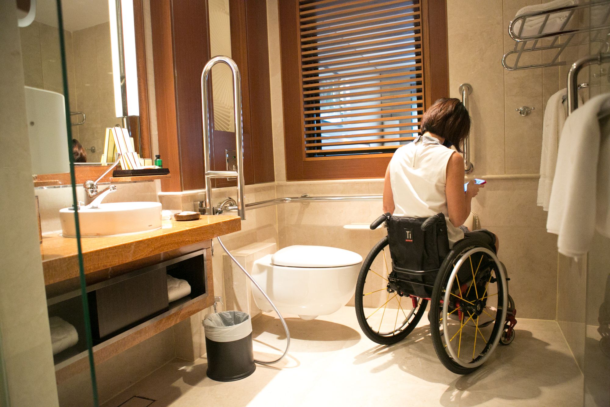 An accessible bathroom with a wheelchair user mapping out the measurements