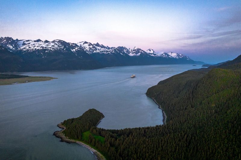 A wheelchair accessible cruise ship going through Alaska's Inside Passage, surrounded by mountains and nature.