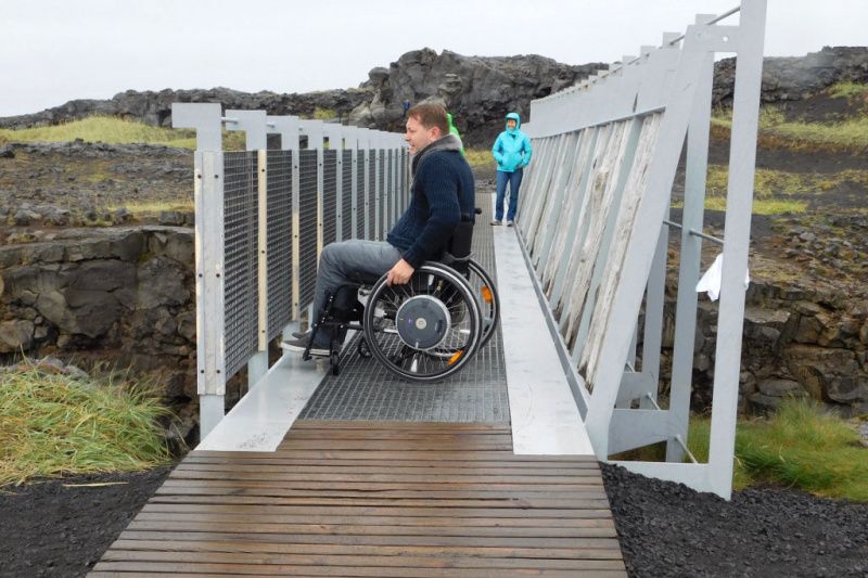 Wheelchair user crossing a bridge in Iceland