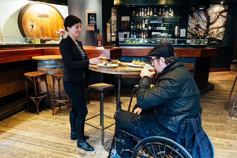 Wheelchair user trying food and beer during Barcelona Local Food Tour