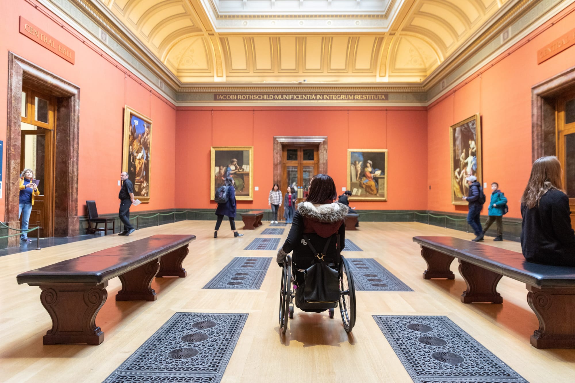 Wheelchair user observing paintings at The National Gallery in London, UK, one of Londons top accessible attractions