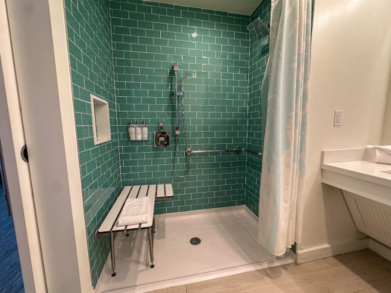 Roll-in shower with a shower seat and grab bars at Margaritaville Beach Hotel - Jacksonville