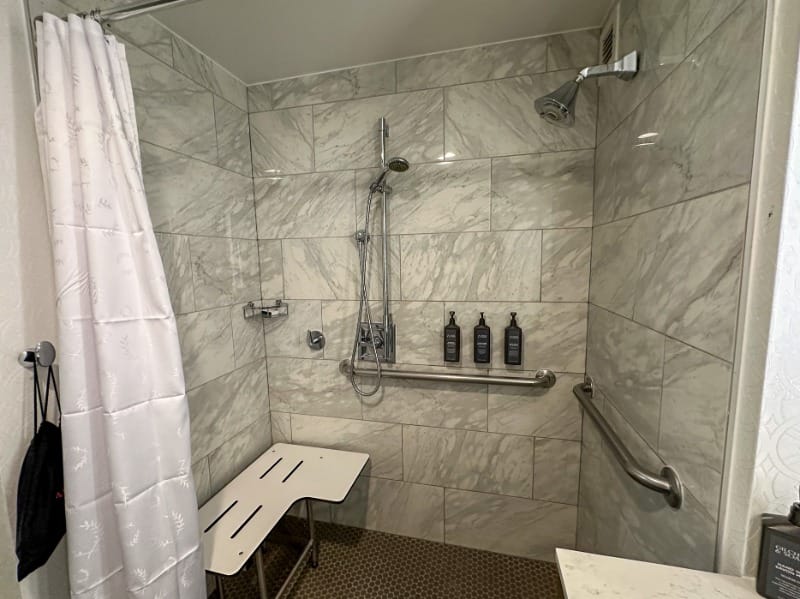 Spacious roll-in shower with a shower seat and grab bars at Sheraton Jacksonville Hotel