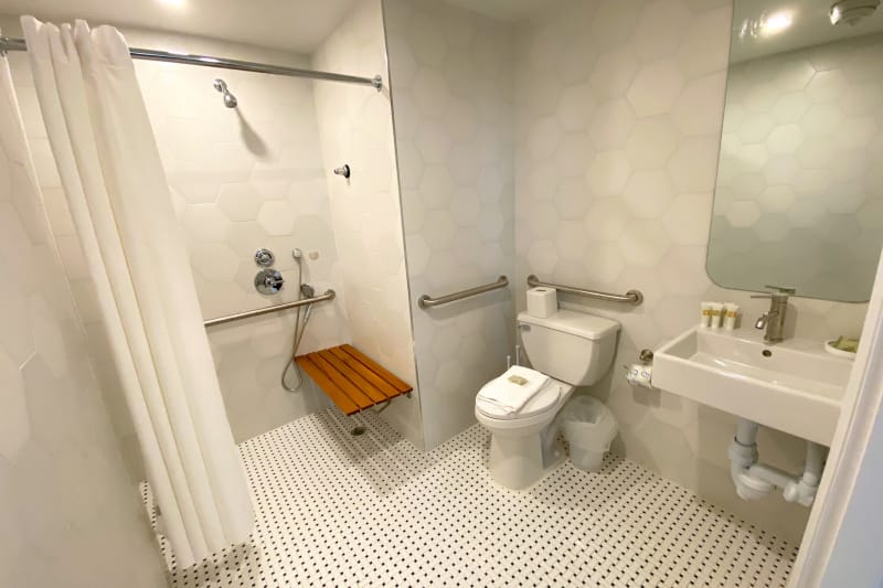 Accessible roll-in shower with a shower bench, toilet grab bars, and turning space at the Sonder I Flatiron