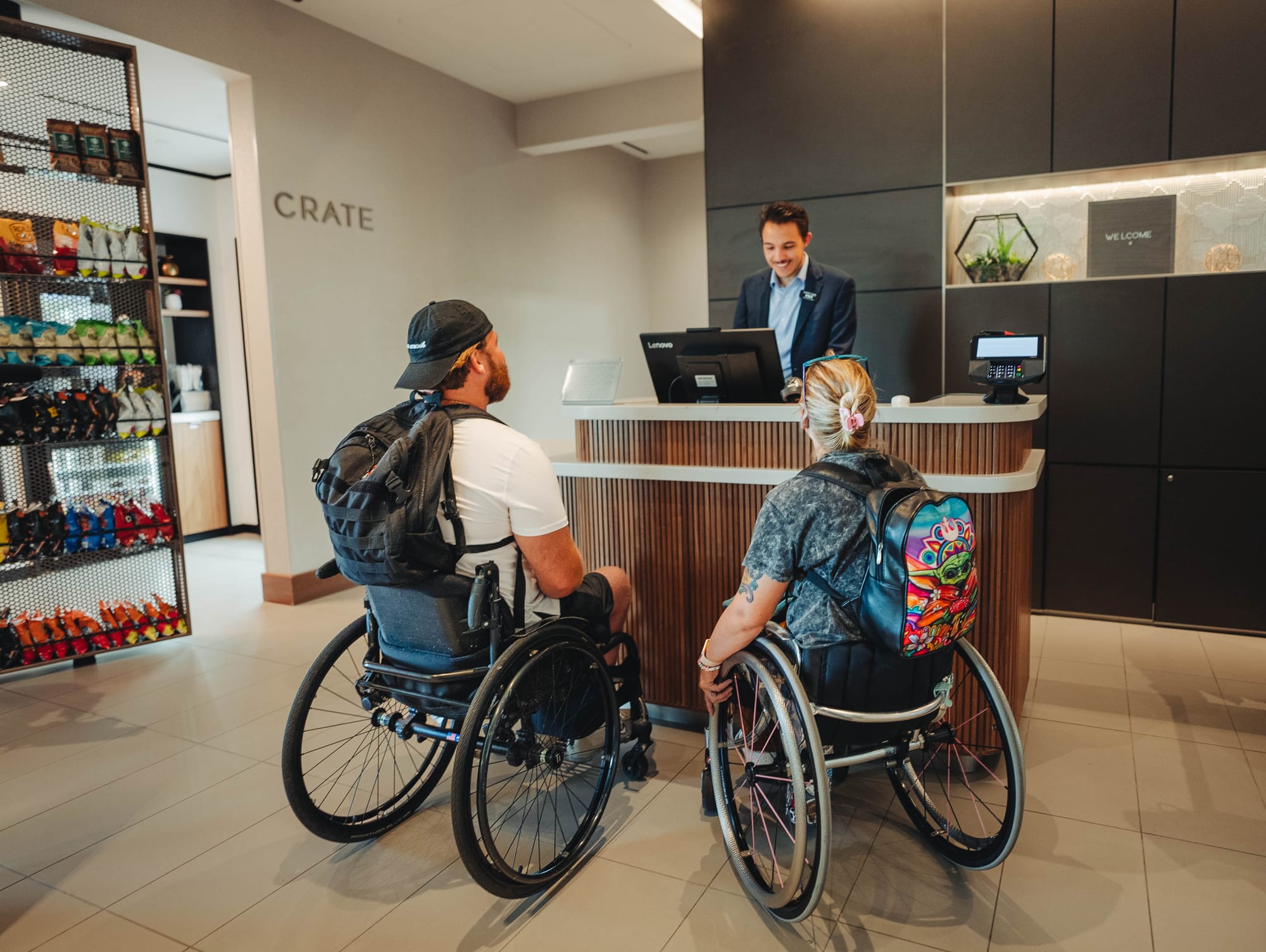 two wheelchair-users checking into an accessible hotel