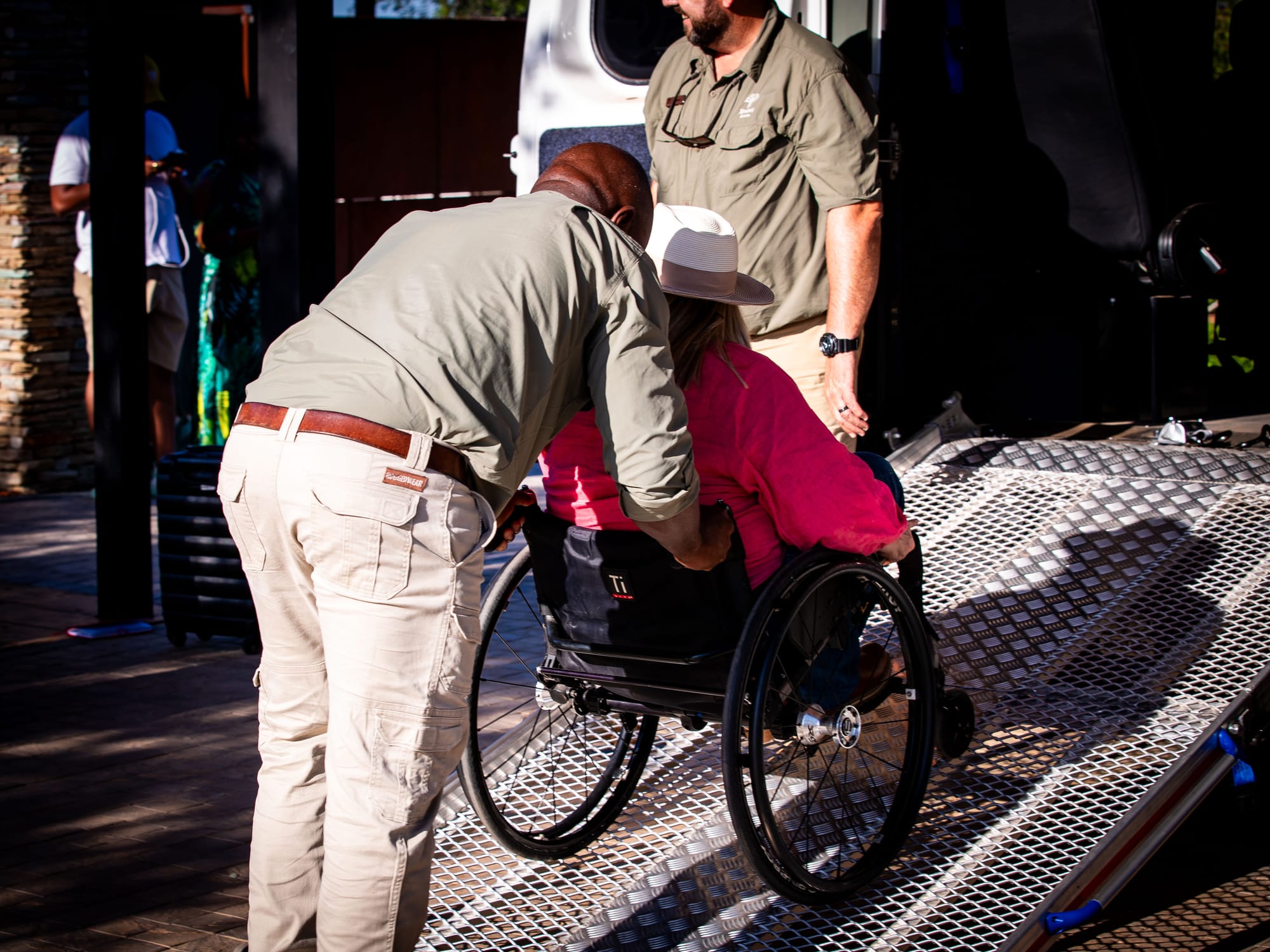 Wheelchair-user getting assisted up a ramp into the adapted van