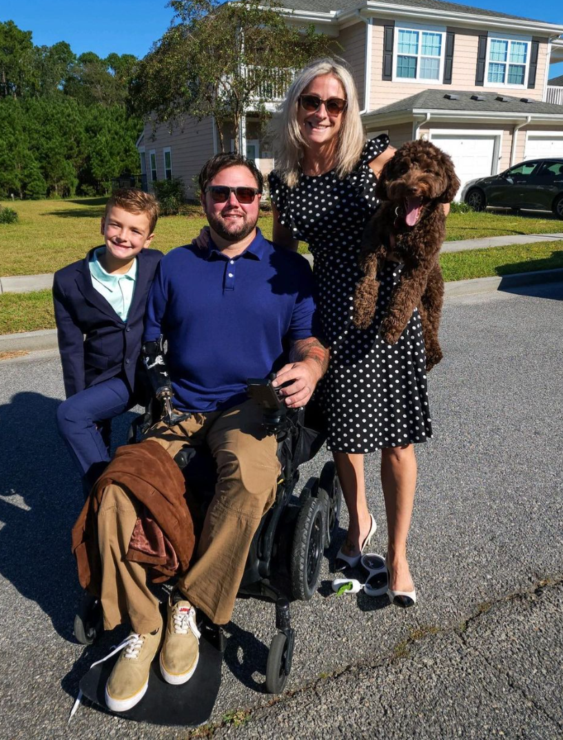 Ryan Davis in a wheelchair next to his family. His wife, Asia, and son, Knox