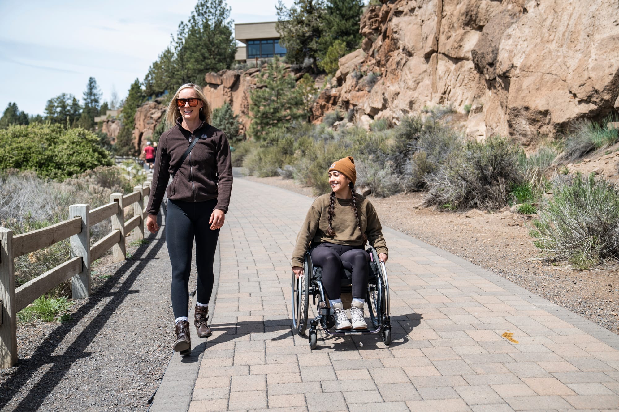 A wheelchair user and her companion strolling on Riverbend South Access in Central Oregon