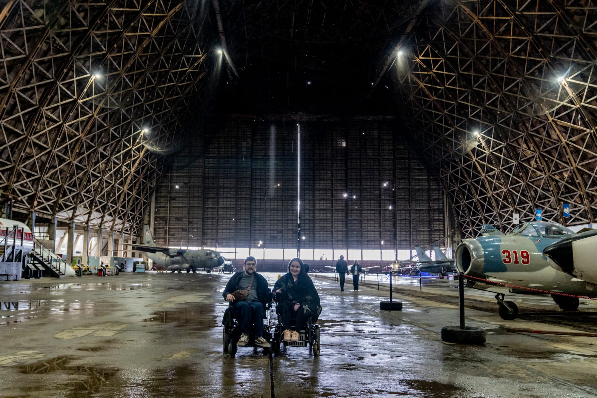 Wheelchair users inside the Tillamook Air Museum with planes behind them