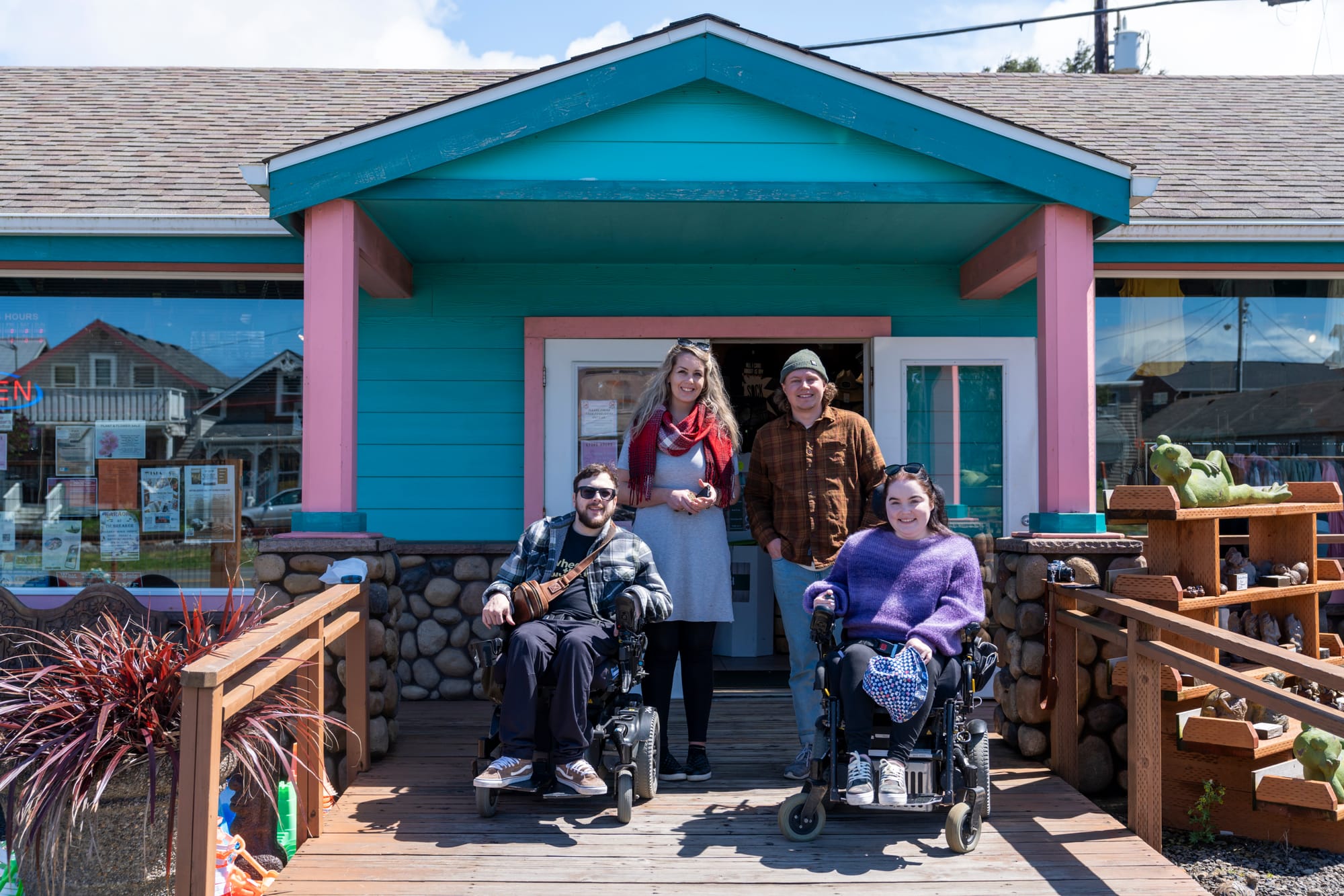 Two wheelchair users and companions posing in front of shop in Rockaway Beach, Oregon