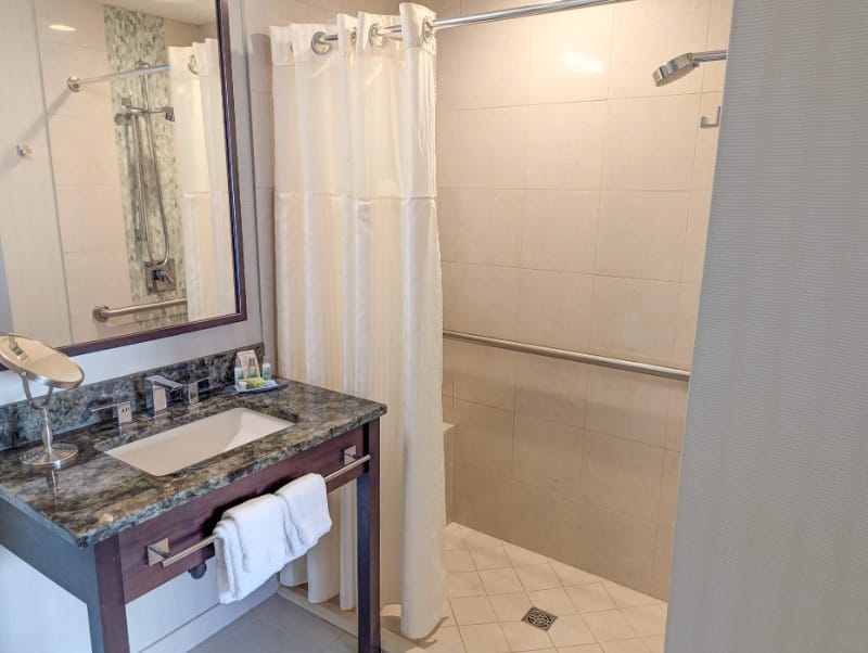 An accessible bathroom with a roll-in shower, grab bars, and shower seat at Bell Tower Hotel