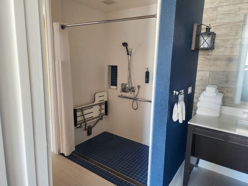 Accessible roll-in shower with a shower seat and grab bars at The Waterfront Beach Resort, a Hilton Hotel