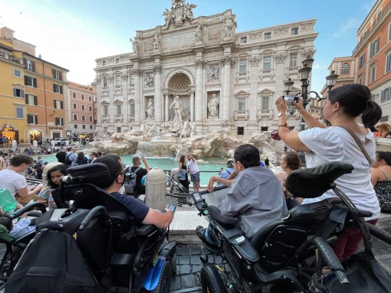 Wheelchair users on a group trip in Italy, taking pictures of Trevi Fountain in Rome