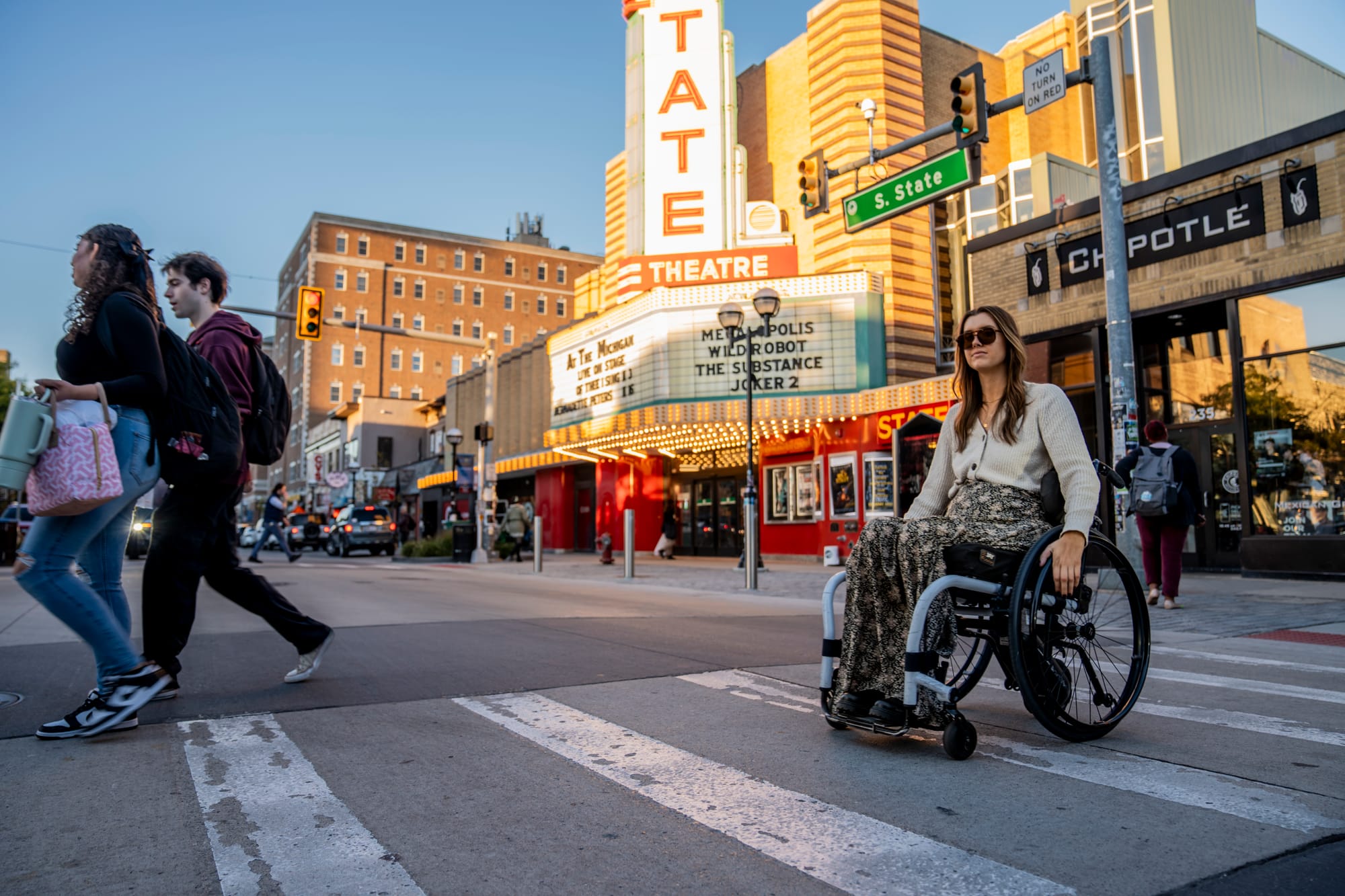 Wheelchair-user exploring downtown Ann Arbor with Michigan Theatre in background