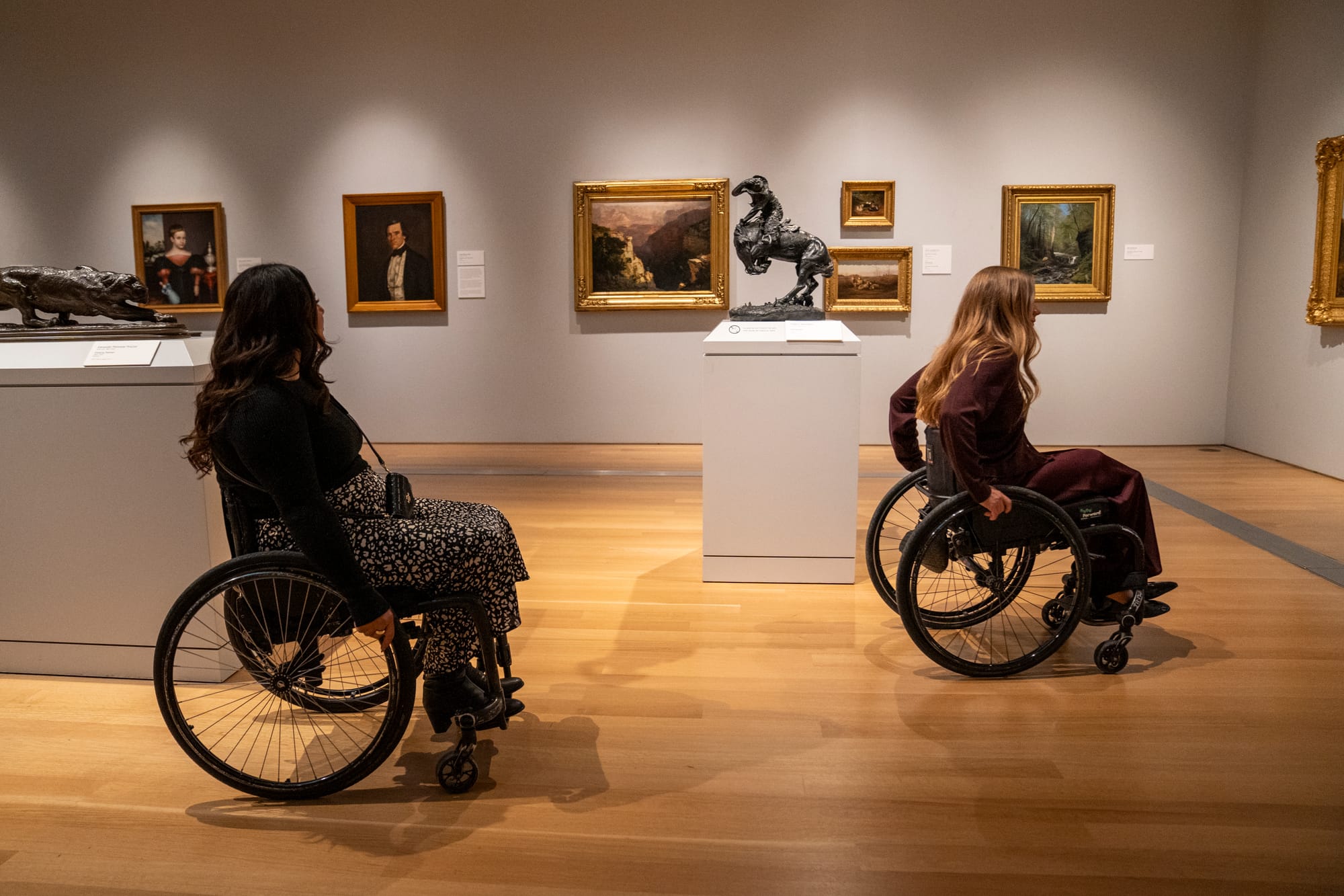 Two wheelchair users viewing art at Grand Rapids art Museum