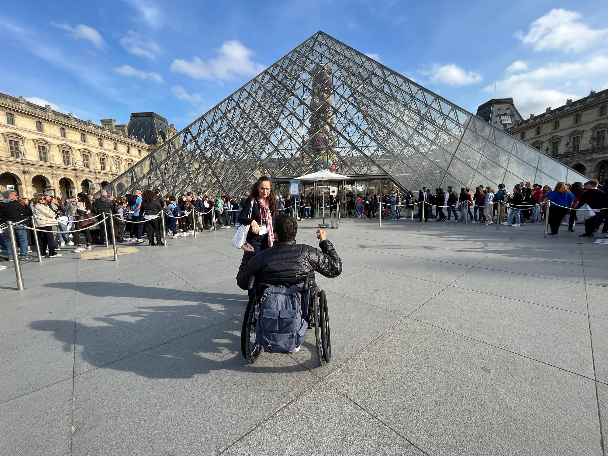 Wheelchair user chatting with staff at Louvre, Paris