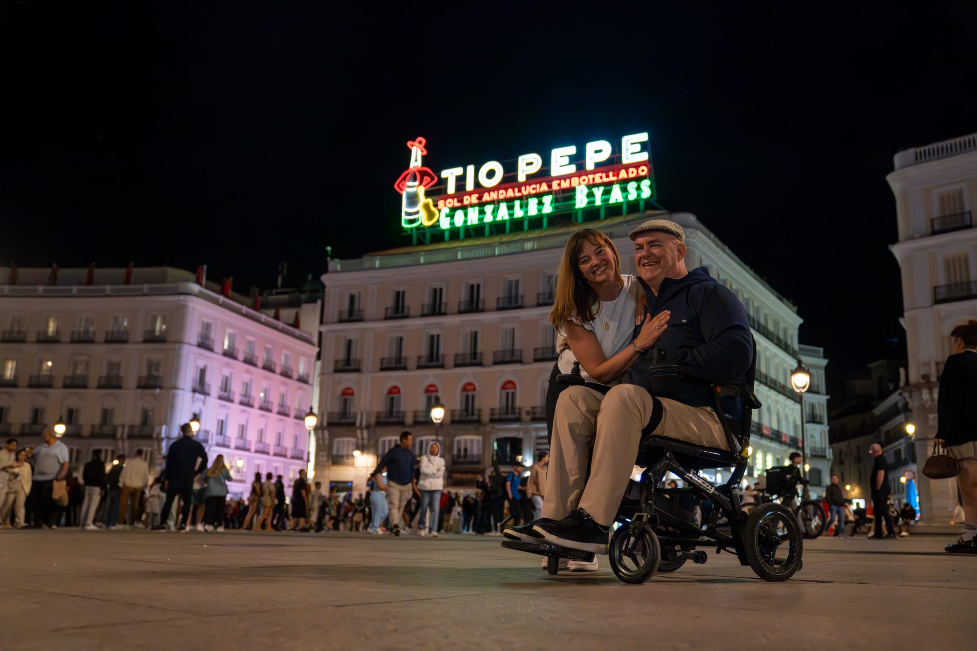 Wheelchair user and companion in front of Tio Pepe sign in Madrid