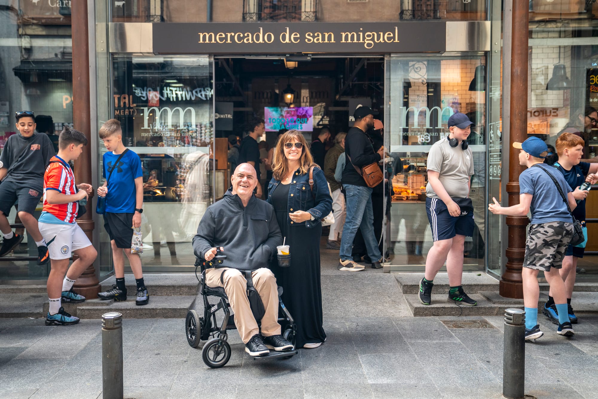 Wheelchair user and companion in front of Mercado de San Miguel in Madrid
