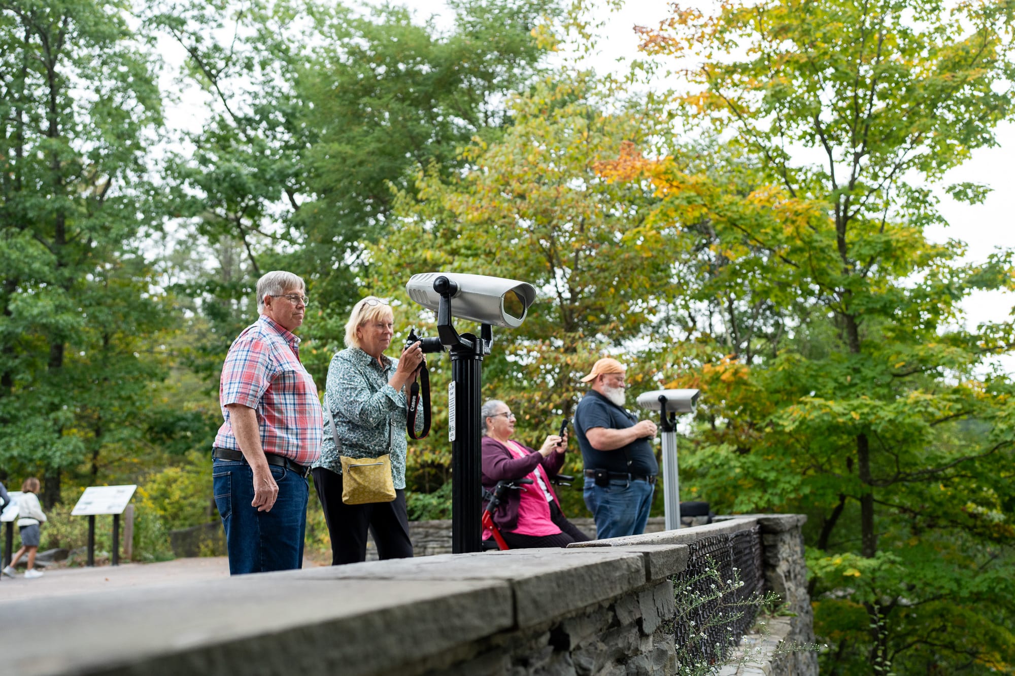 Wheelchair user and elderly couple looking through observation viewers at Taughannock Falls State Park