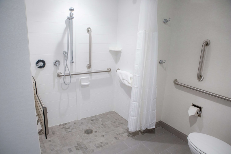 Accessible roll-in shower with a seat and grab bars at Hilton Garden Inn