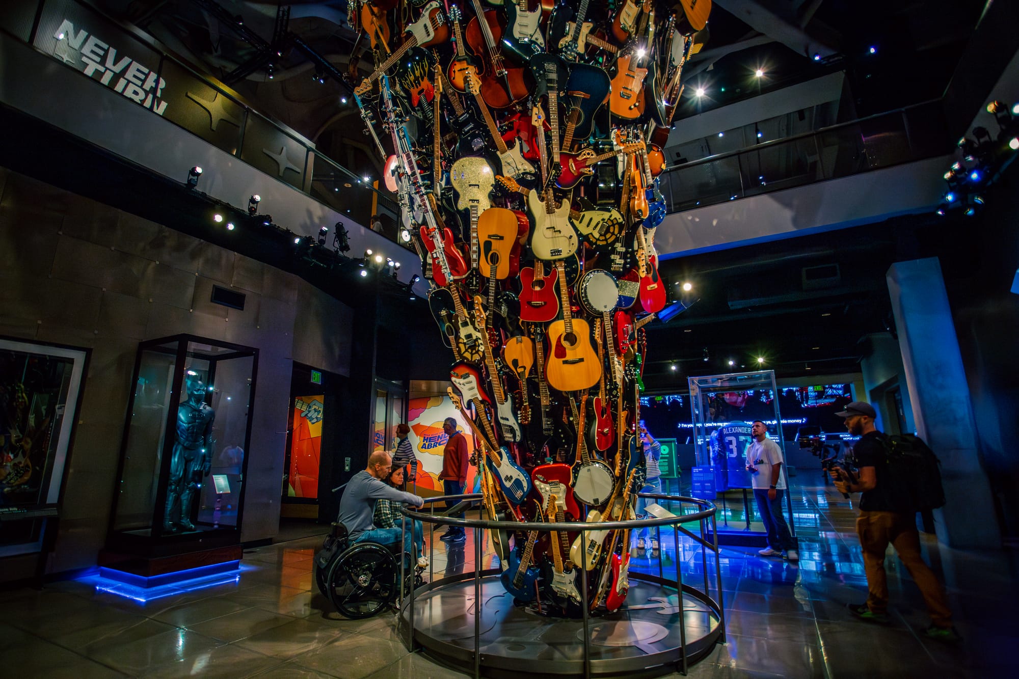 Two wheelchair users looking at the guitar exhibit at the Museum of Pop Culture