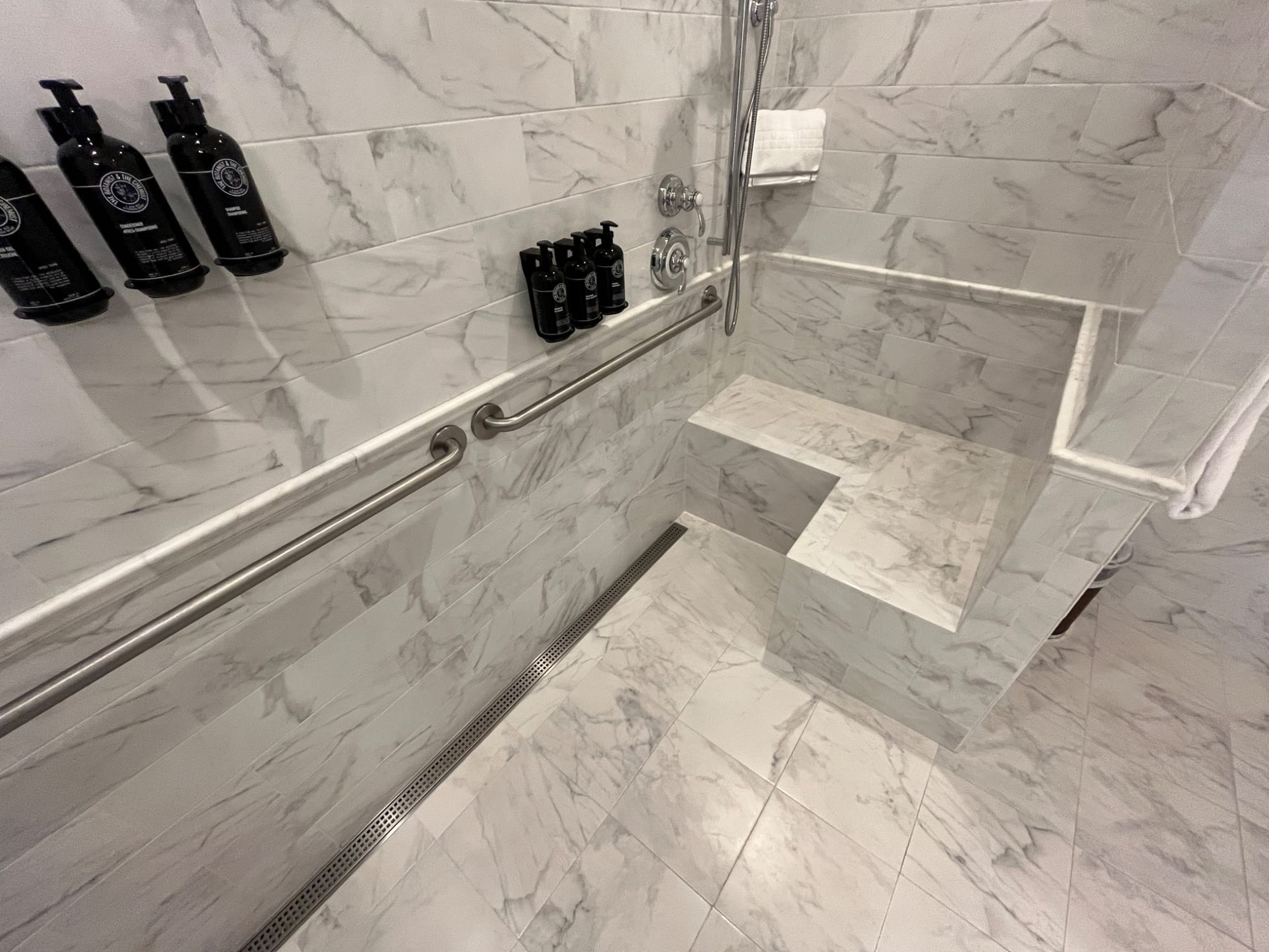 Roll-in shower with bench and grab bars at Mirror Lake Inn