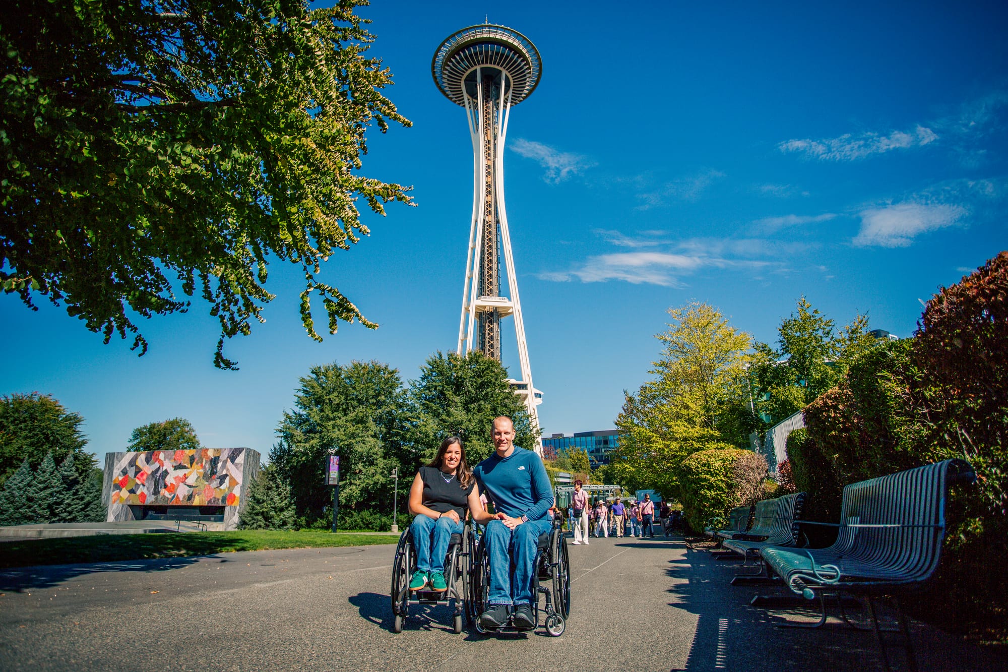 Maggie and Brad, two wheelchair users, posing in front of the Space Needle in Seattle