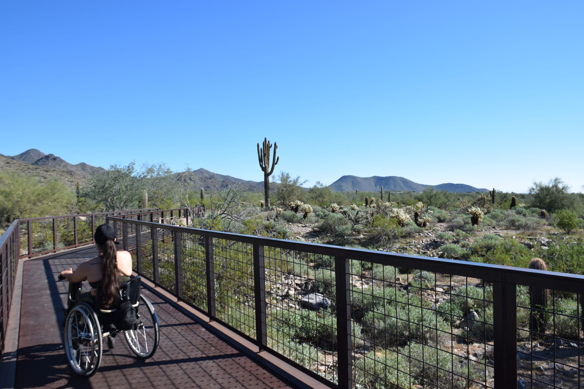 Kerry, wheelchair user, on the Gateway Trailhead connecting to Bajada Nature Trail