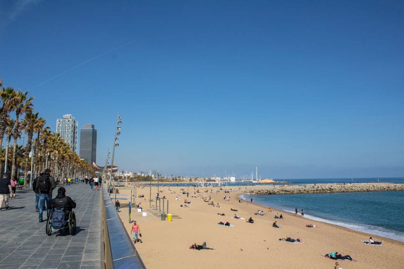 View of Barceloneta Beach in Barcelona with wheelchair user along the walking path