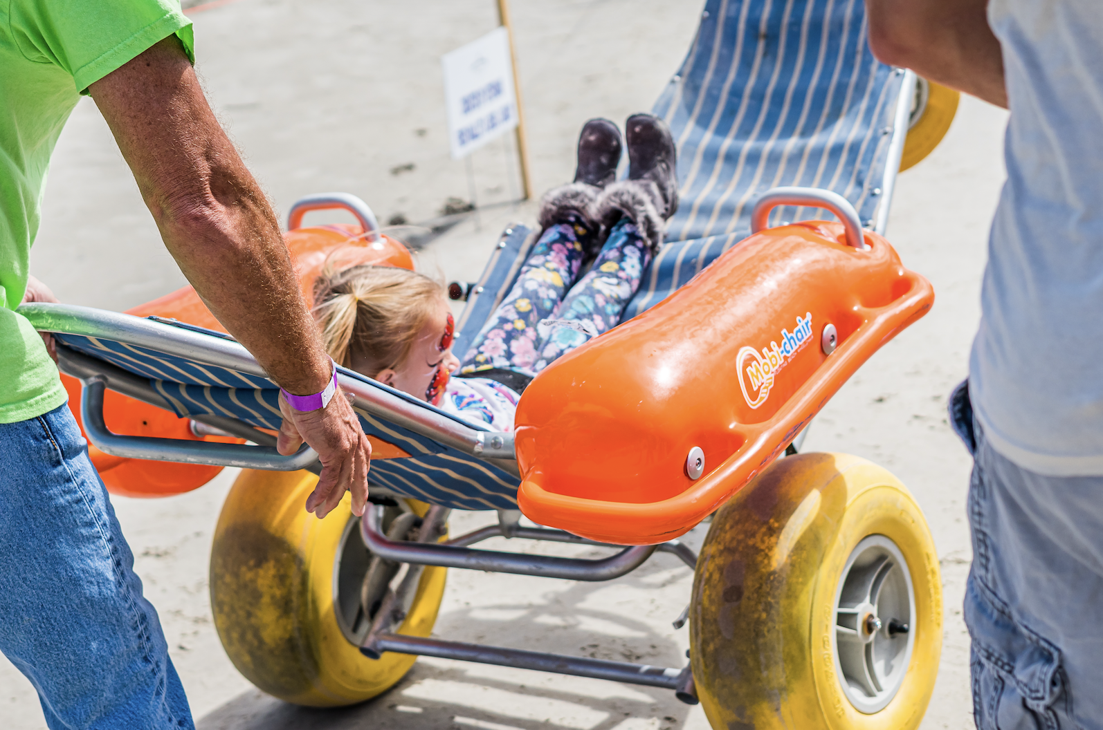 Girl on a beach wheelchair being pulled, in Port Aransas
