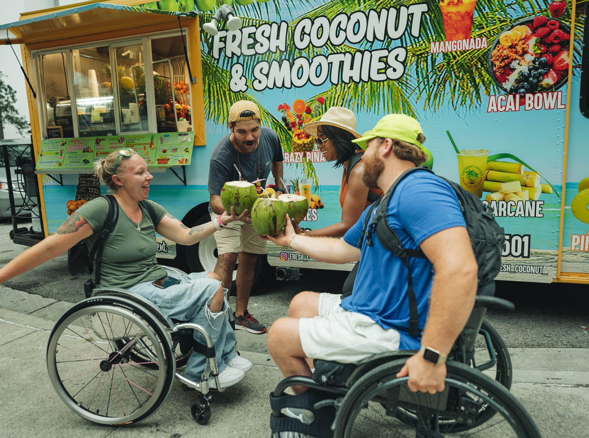 Two wheelchair users and companions cheers-ing refreshing smoothies in Fort Lauderdale