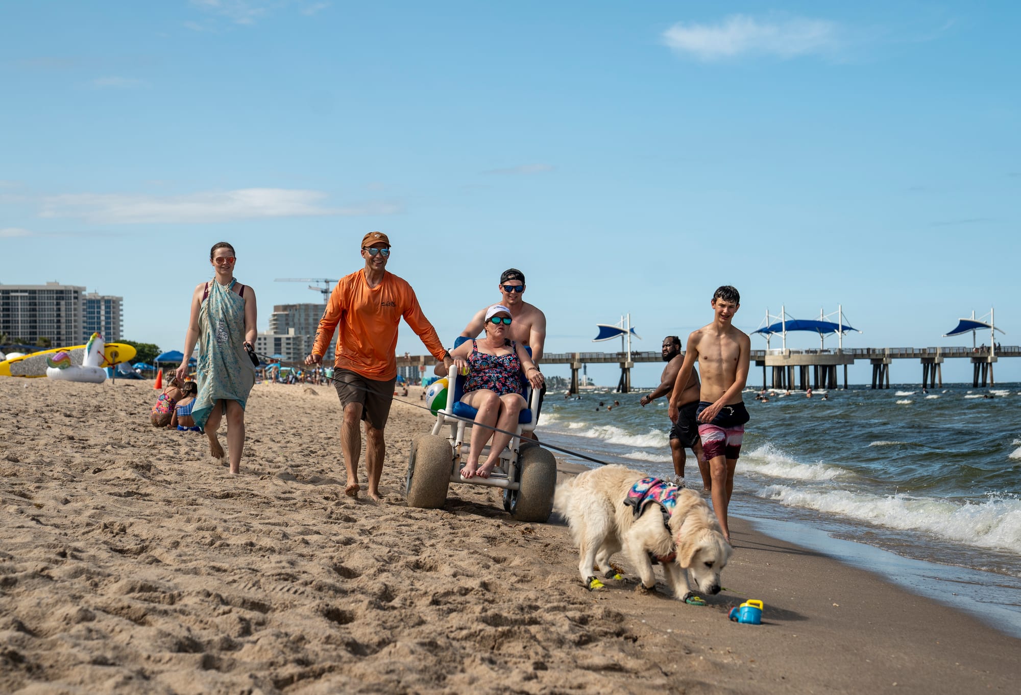 Kristy Durso, a wheelchair user, her family and dog strolling along beach in Fort Lauderdale