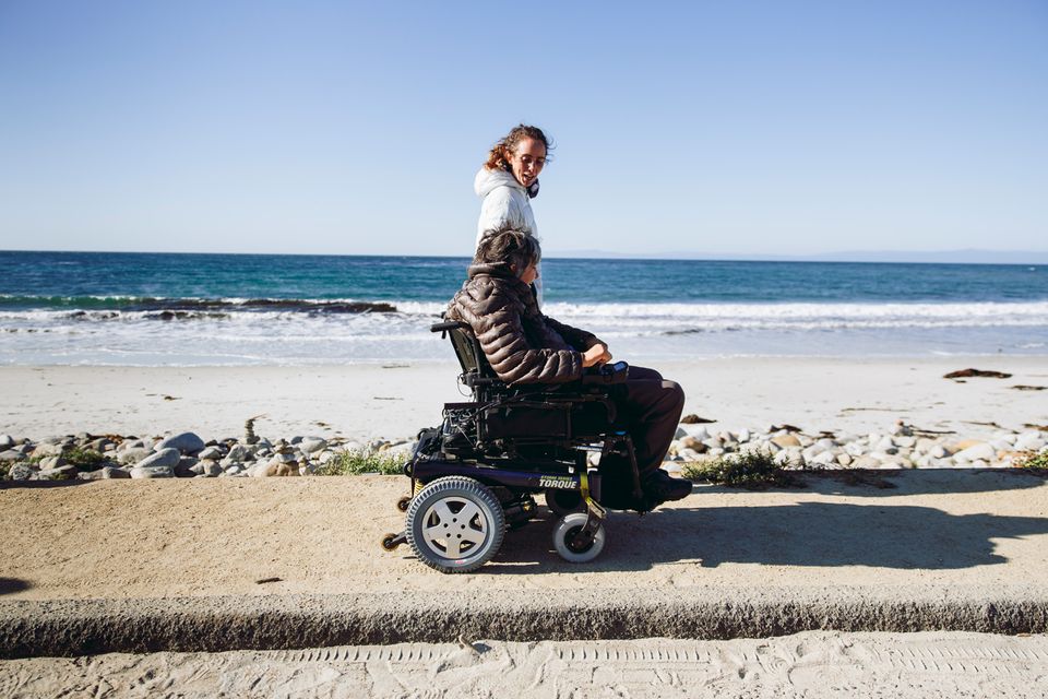 Wheelchair-user and companion walking along the beach