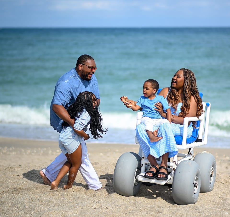 Lizzy in a beach wheelchair, with her husband and two kids, at Jensen Beach in Martin County, Florida